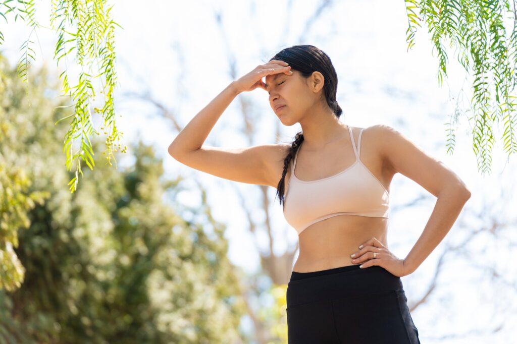 Hispanic young woman expresses a headache while doing sports